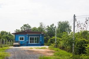 uma única casa azul com um carro entre as árvores. foto