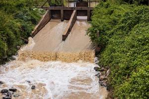 a água selvagem flui fortemente do açude transbordando. foto