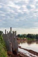 muitas colunas de concreto formam uma longa parede perto da margem do rio. foto