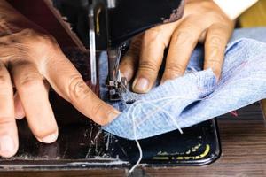 mão feminina e jeans com máquina de costura velha. foto