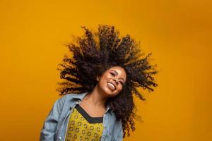 retrato da beleza da mulher afro-americana com penteado afro e maquiagem glamour. mulher brasileira. mestiço. cabelo encaracolado. Penteado. fundo amarelo. foto