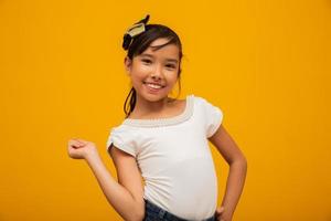 linda garota asiática sentada no fundo amarelo. menina asiática feliz sorrindo. foto