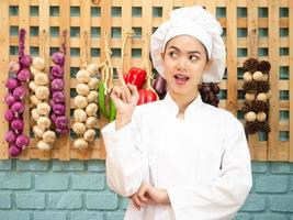 mulher asiática com uniforme de chef está cozinhando na cozinha. cozinheiro feminino retrato sorrindo com espaço de cópia. foto