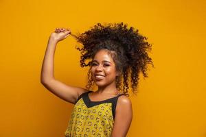 retrato da beleza da mulher afro-americana com penteado afro e maquiagem glamour. mulher brasileira. mestiço. cabelo encaracolado. Penteado. fundo amarelo. foto