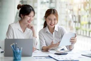 duas jovem empresária asiática discutem com a nova apresentação da ideia do projeto de inicialização, analisam o planejamento e as estatísticas financeiras e o mercado de investimentos no escritório. foto