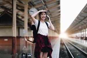 mulher jovem viajante procurando amigo planejando viagem na estação de trem. conceito de estilo de vida de verão e viagens foto