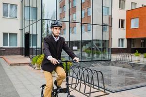 jovem empresário masculino com bicicleta e xícara de café ou chá caminhando ao ar livre foto