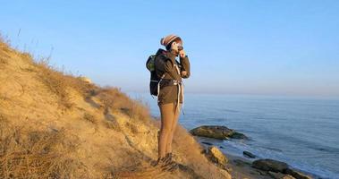 jovem viajante feminina com mochila e câmera de filme retrô viajar nas montanhas de outono perto do mar foto