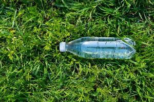 garrafa plástica de água fresca na grama verde foto