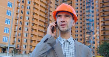 retrato de especialista em construção em capacete laranja e colete de segurança contra grande edifício foto