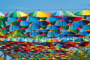 decoração ao ar livre com muitos guarda-chuvas coloridos contra o céu azul e sol foto