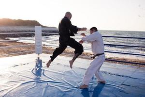 lutadores de karatê estão lutando no ringue de boxe de praia de manhã foto