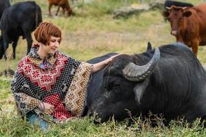 jovem mulher vestida com um passeio de poncho em grande búfalo