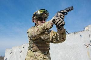 soldado masculino em uniforme da OTAN com arma de mão ao ar livre no campo foto