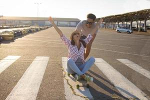 jovem casal andando de skate durante o nascer do sol foto