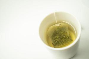 saquinho de chá verde em uma xícara. xícara de chá verde aromático sobre fundo branco. xícara com chá verde em isolado. foto