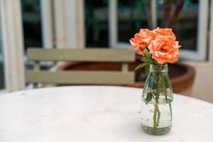 linda flor rosa em vaso decorado na mesa foto