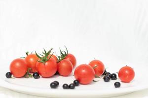 tomates vermelhos frescos com amora no fundo thite, comida saudável para uma alimentação saudável. foto