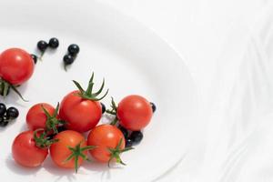 tomates vermelhos frescos com amora no fundo thite, comida saudável para uma alimentação saudável. foto