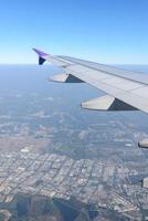 asa do avião voando acima da cidade. vista da janela de um avião foto