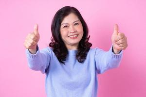 retrato de mulher asiática de meia idade em fundo rosa foto