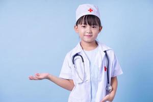 imagem de criança asiática vestindo uniforme médico em fundo azul foto