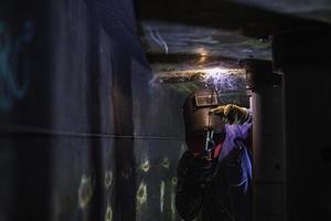 soldar o arco de metal do trabalhador masculino faz parte do óleo do tanque de construção do bico do tanque de máquinas dentro de espaços confinados. foto