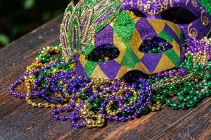 grânulos de cor de carnaval com máscaras na mesa de madeira à luz do sol foto