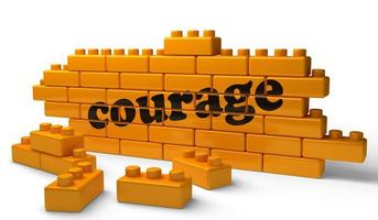 palavra de coragem na parede de tijolos amarelos foto