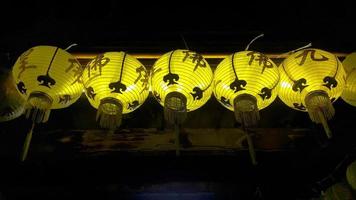 linha de luzes de lanternas de cor amarela penduradas no escuro foto