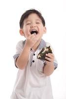 bonita criança asiática comendo bolinho de arroz ou onigiri