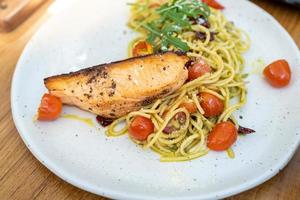 molho pesto verde de macarrão espaguete com filé de salmão grelhado - estilo de comida italiana foto