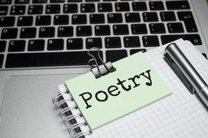 palavras de poesia no papel, laptop de lupa e caneta foto