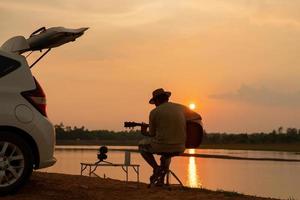 músico, suas férias, um novo estilo de vida normal, piquenique e carro durante o pôr do sol foto