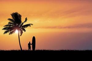 os surfistas de silhueta ouvem na praia com coqueiros pela manhã. foto