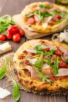 pizza italiana com queijo parmesão, presunto e rúcula foto
