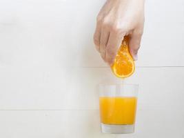 mão de homem, espremendo a laranja no copo de suco de laranja