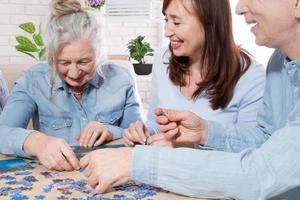 idosos da família de meia-idade colecionam quebra-cabeças na mesa da sala foto
