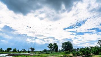 bela luz em nuvens de tempestade escuras e dramáticas após a chuva. campo de plantas verdes e lagoa sobre céu azul dramático. paisagem de céu de natureza e nuvens, fundo impressionante dramático, conceito de relaxamento foto