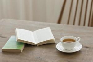 uma única xícara de chá em uma mesa de madeira com livros foto