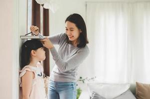 mãe medindo a altura da menina perto da parede foto