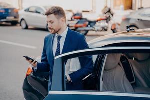 gerente executivo de sucesso em terno elegante formal de smoking saindo do carro foto