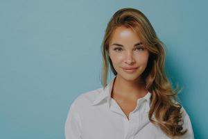 retrato de jovem modelo feminino caucasiano com cabelo loiro tingido sorrindo para a câmera sobre fundo azul foto