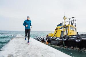 jovem corredor masculino treinando ao ar livre em tempos de inverno, homem correndo na neve foto