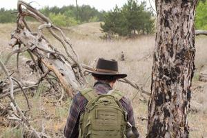 vista traseira do jovem alpinista masculino com chapéu de cowboy caminhando ao ar livre em dia de verão. viajante hipster. foto