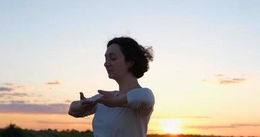 mulher praticando qigong em campos de verão com belo pôr do sol no fundo foto