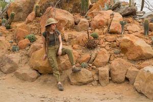 jovem viajante masculino no deserto, mulher alpinista no jardim de cactos foto