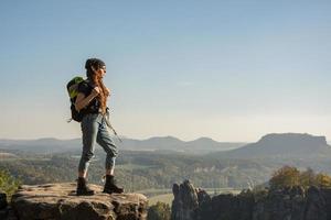 jovem viajante com baclpack fica no penhasco nas montanhas foto
