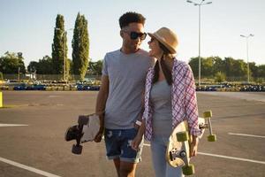 casal jovem feliz andando de skate durante o nascer do sol foto