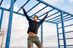 treinamento masculino jovem em forma faz exercícios ao ar livre na praia foto